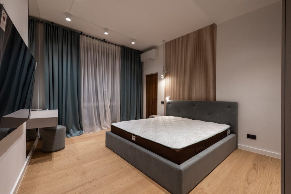 pexels-photo-6585762 Modern TV set and comfy bed in stylish room decorated with lamps and curtains