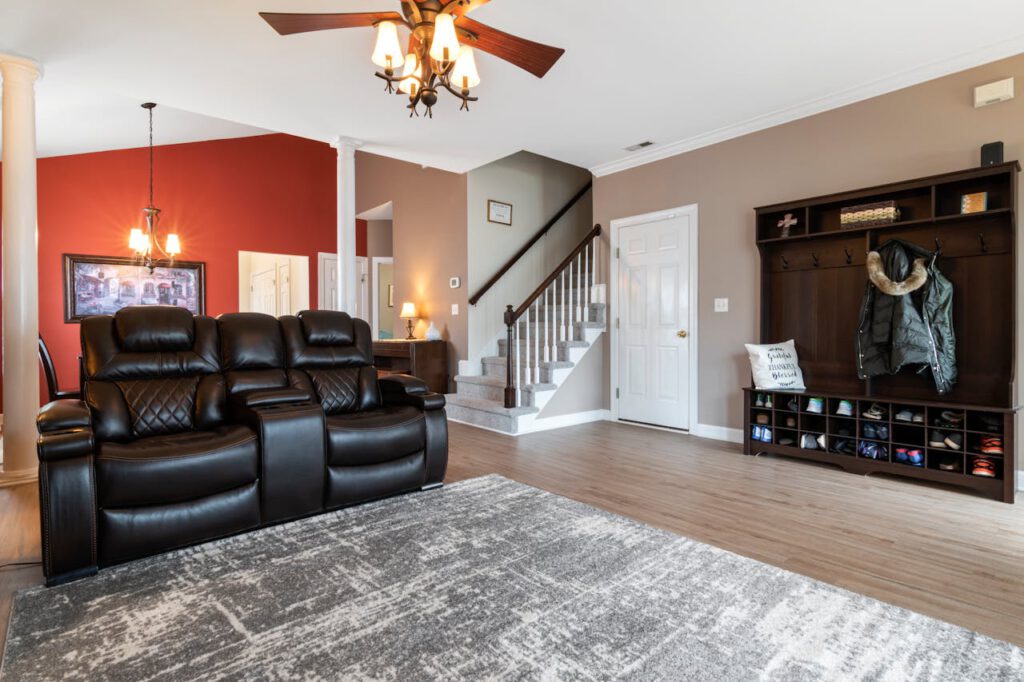 pexels-photo-6835160 Spacious living area featuring black leather couches, a chandelier, and modern interior design elements.